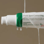 Tube of dark spot correcting cream with visible text on a beige background