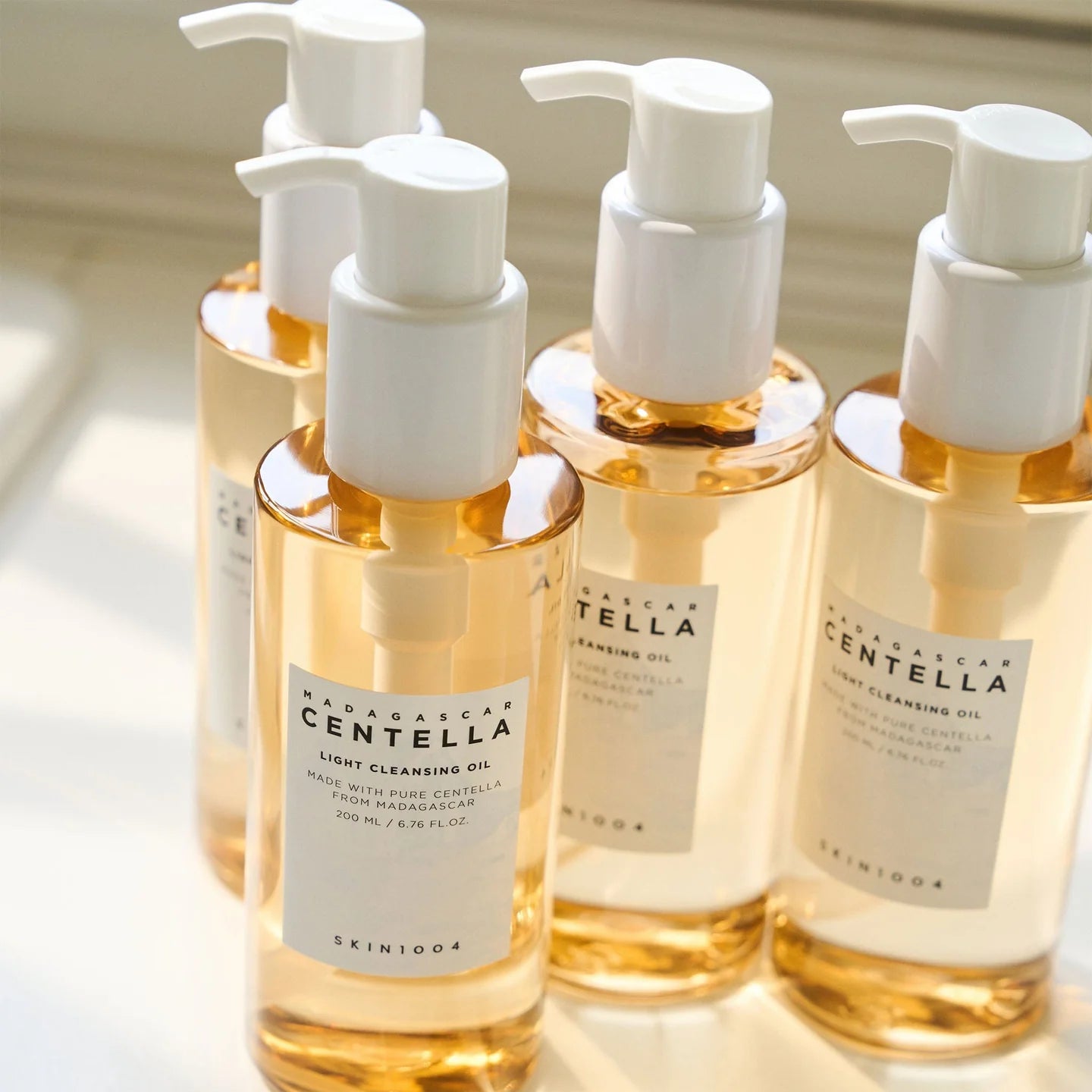 Five bottles of Skinfood Madagascar Centella cleansing oil with pump dispensers on a light background.