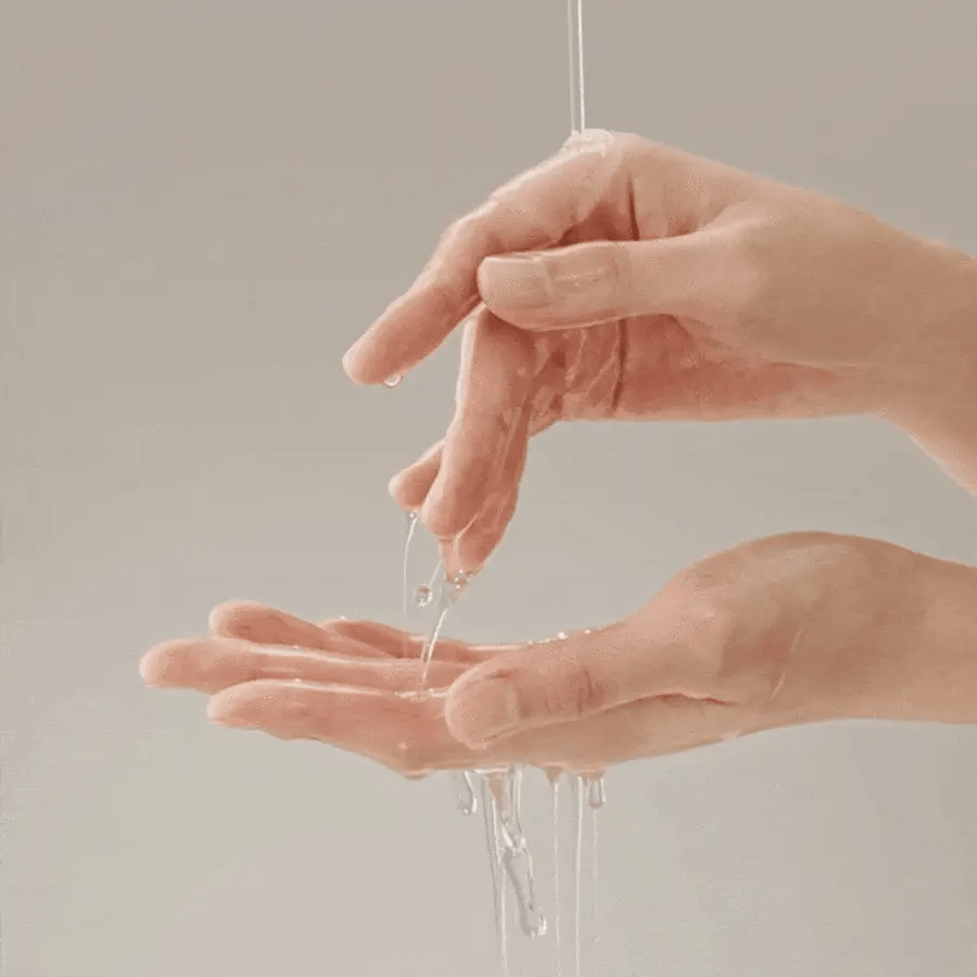 Hands holding a clear liquid against a neutral background